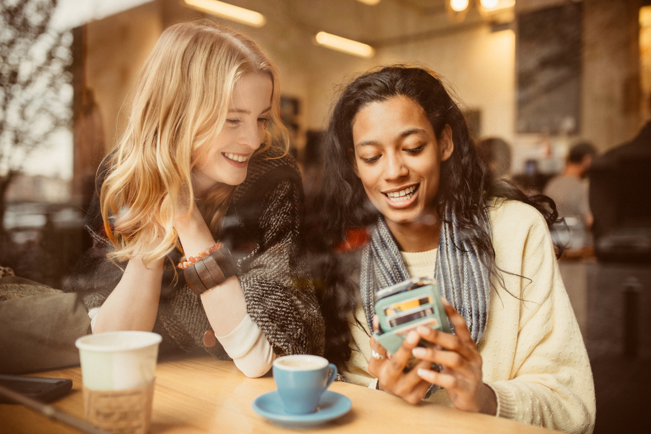 Two Friends Looking At A Phone With Cards In The Case