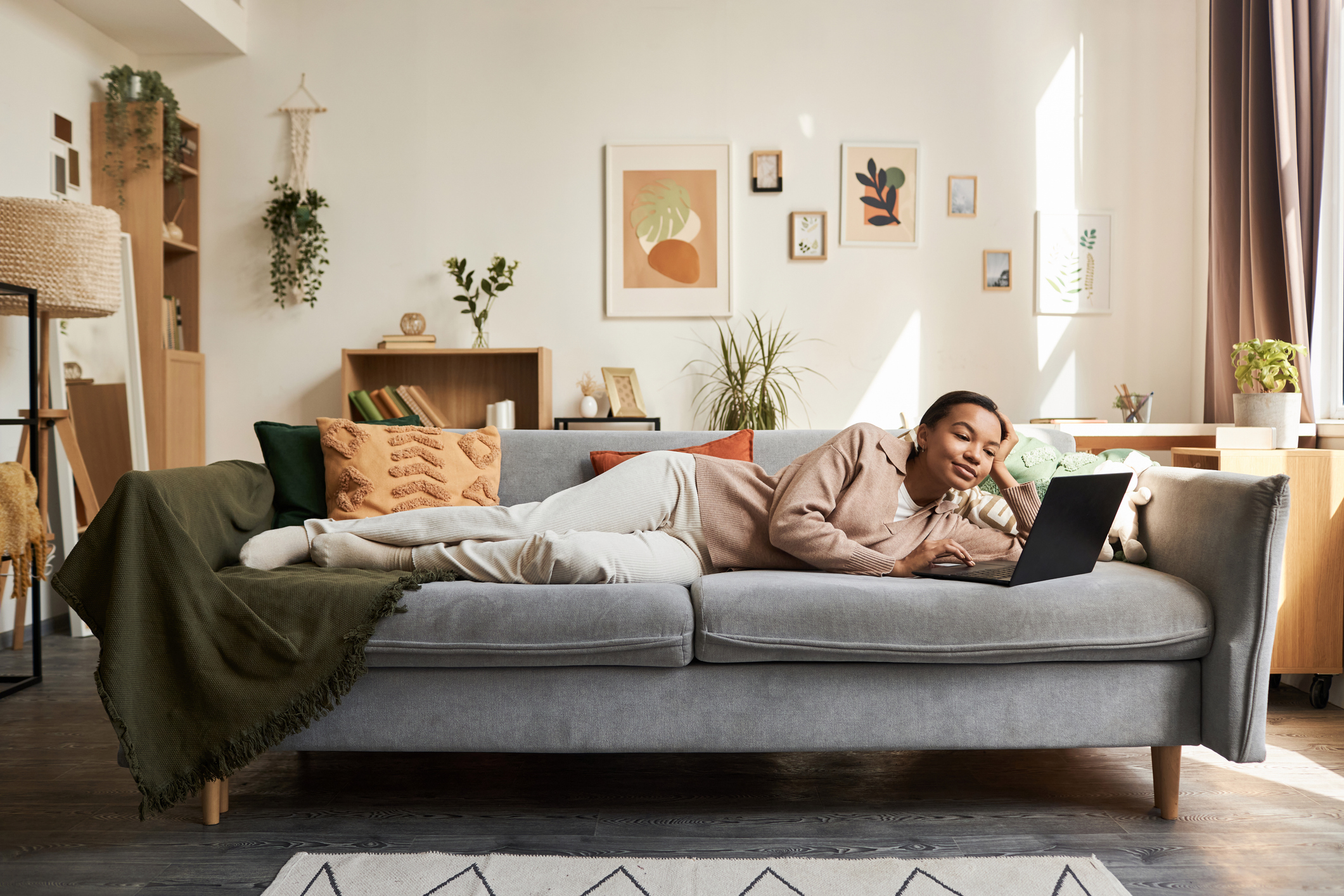 Woman laying on her sofa next to a large window