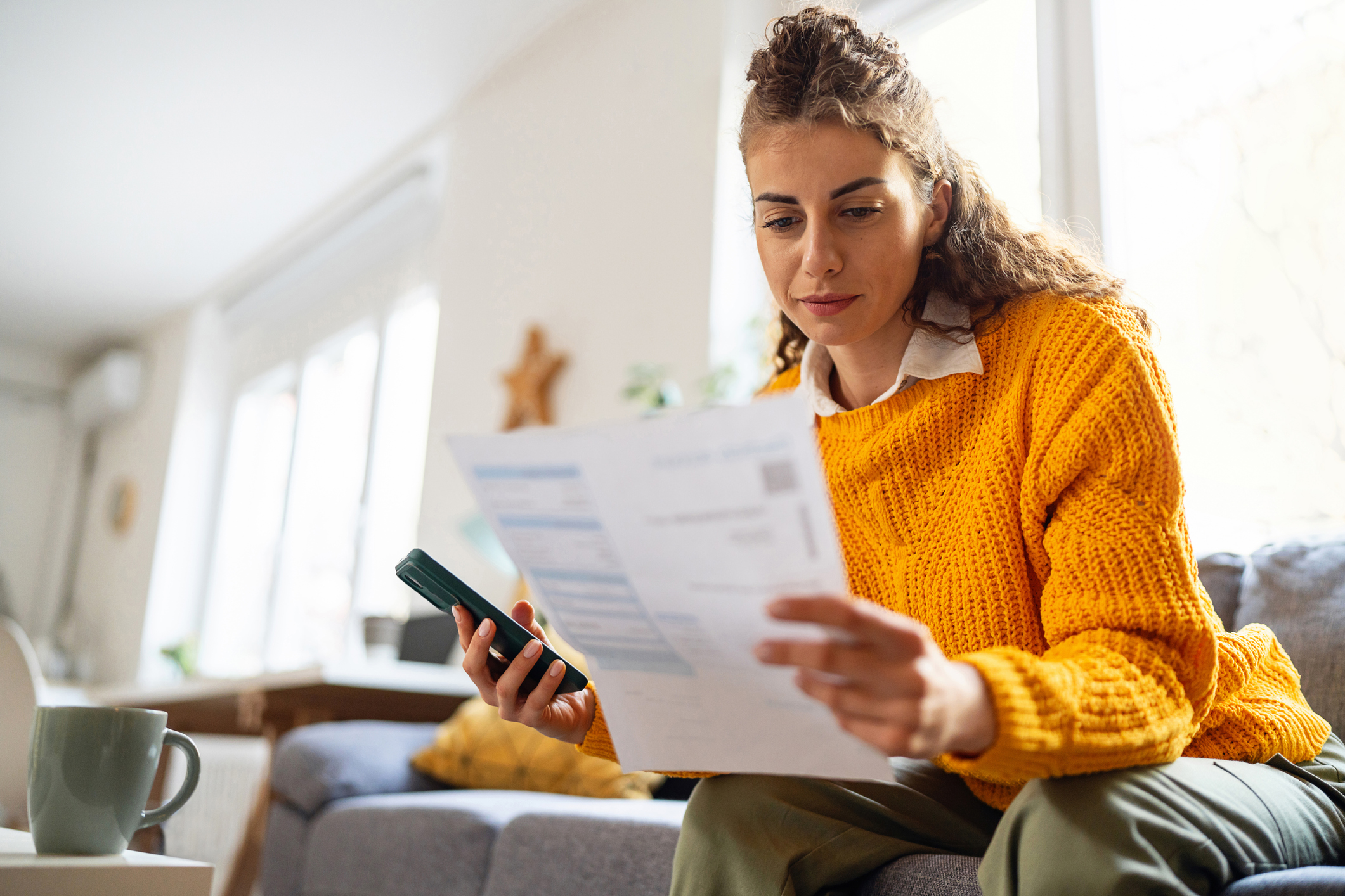 Woman In A Yellow Jumper Opening A Bill