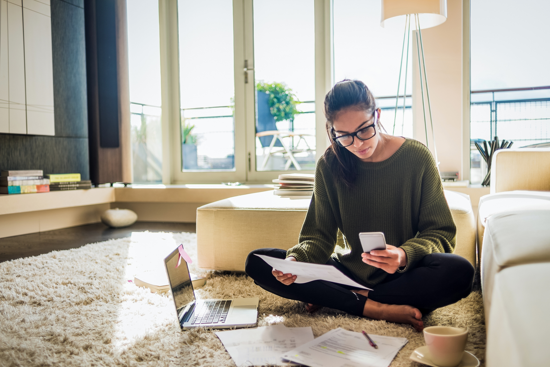 Woman looking through her finances with a phone in her hand